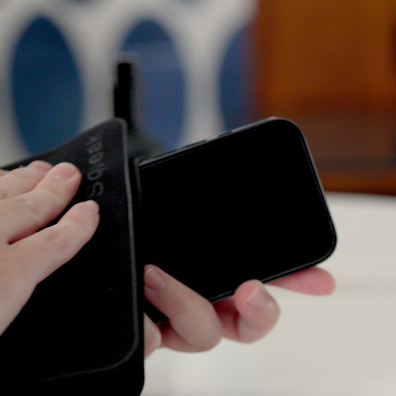 a user wiping and polishing their phone clean with a Squeak Polishing Cloth