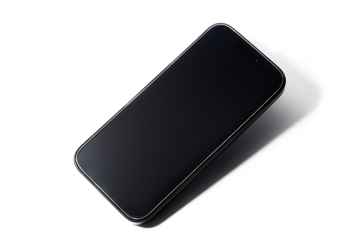 A smartphone with a clean, reflective screen is shown on a white surface, angled slightly to the side.