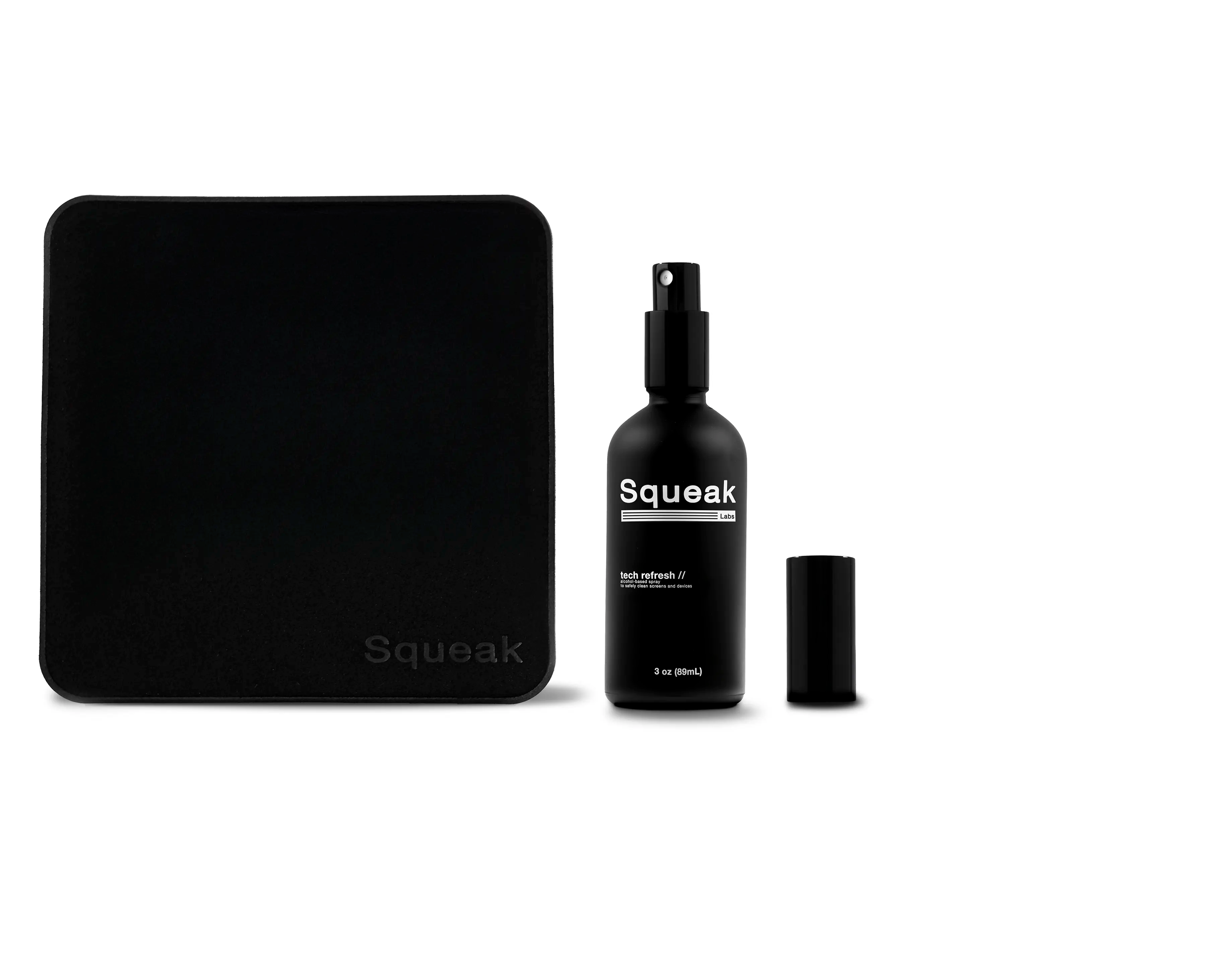 A black Squeak Labs “Tech Refresh” screen-cleaning spray bottle is shown with its cap removed, placed beside a large black microfiber cleaning cloth on a white background.